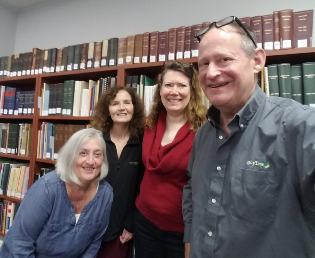 Four people smiling in front of bookcases